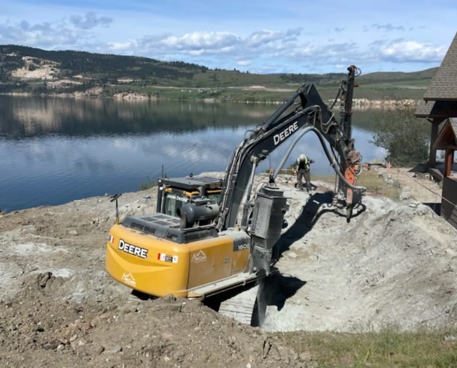 McCaw's excavator-mounted drill installing anchors beside a lakeshore